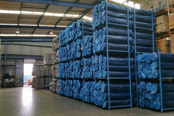 Blue stack racks storing rolled textile fabric in warehouse